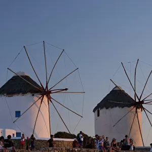 People Watching The Sunset Beneath Old Windmills; Mykonos Town, Mykonos, Cyclades, Greek Islands, Greece
