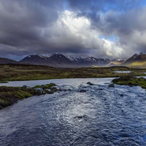 River in moor landscape with cloudy sky and mountains in the background at Rannoch Moor in Scotland, United Kingdom
