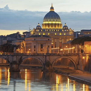 Rome, Italy. Sant Angelo bridge and St Peters Basilica at dusk. The historic centre of Rome is a UNESCO World Heritage Site