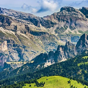 Scenic vista of the grassy mountain side and the jagged mountain tops at the Sella Pass in the Dolomites in South Tyrol, Italy