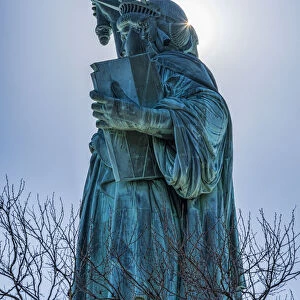 Sun Shining Behind Statue Of Liberty Torch, Liberty Island; New York City, New York, United States Of America