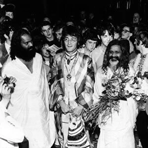 The Beatles with the Maharishi Mahesh Yogi who is clutching bundles of flowers Beatles