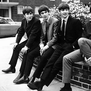 The Beatles pose sitting on a wall, 1963. Left to right: John Lennon