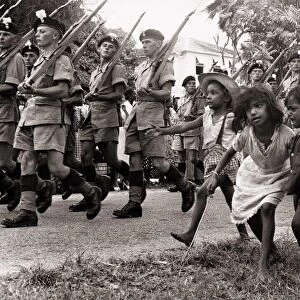 British soldiers marching in Georgetown British Guiana followed by some children in 1953