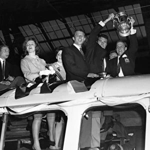 Manchester United captain Noel Cantwell (right) proudly holds aloft the FA Cup trophy to