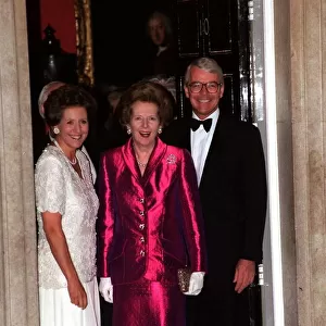 Margaret Thatcher wearing a long pink dress stands with Prime Minister John Major