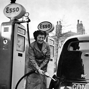 Petrol pump attendant filling up a car at an Esso service station. January 1953