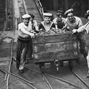 Sailors of the Royal Navy pulling a coal truck as they help out at the pits during