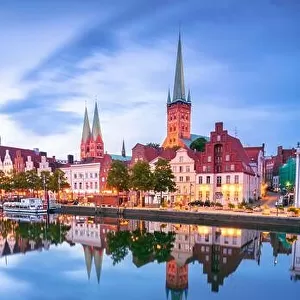 Lubeck, Germany. Cityscape image of riverside Lubeck with reflection of the city in Trave River at sunset
