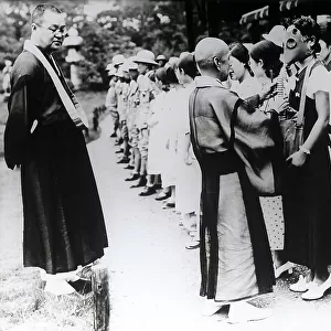 Buddhist priests giving instructions to a large group pf young men for defense air manoeuvres