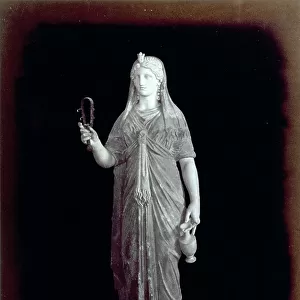 Roman statue of Isis. The goddess, dressed in classic attire, holds a sistrum in her right hand, and a pitcher in her left